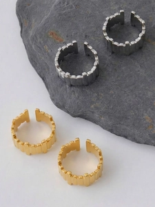 Detailed view of silver and gold irregular vertical stripe rings on dark natural stone