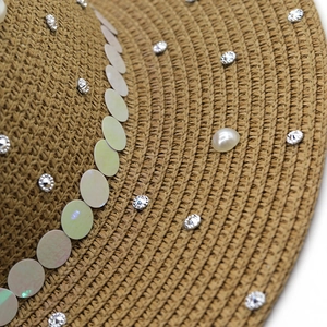 Detail shot of woven straw hat featuring elegant pearls, rhinestones and sequins