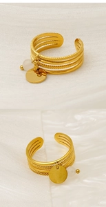 Detail of gold multi-layer adjustable ring with white translucent bead and metal pendant