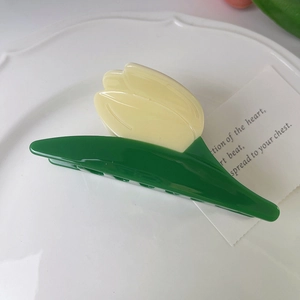 Close-up of a yellow tulip hair claw clip on a white plate with green leaf detail