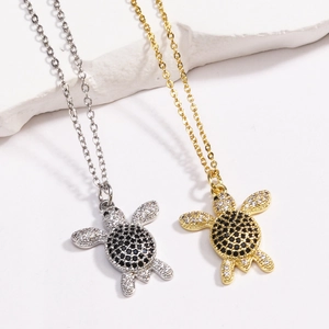 Detail of silver and gold turtle necklaces featuring crystal zircons on stone background