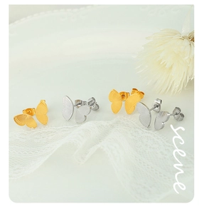 Detailed close-up of butterfly-shaped titanium steel stud earrings in gold and silver finish