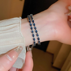 Detail of adjustable silver bracelets featuring teardrop and square blue zircons on wrist