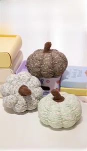 Detailed close-up of three floral pumpkin plush pillows in pink, grey, and green colors