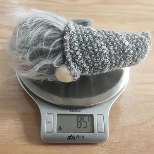 Detailed view of grey striped gnome decoration being weighed on a digital scale at 85.7g
