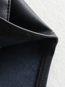 Macro detail of the fine stitching and texture on the black leather vest edge