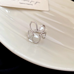 Macro shot of silver open ring with irregular floral design on white ceramic plate