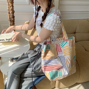 Detail of colorful striped canvas tote bag showing velvet texture and double shoulder straps