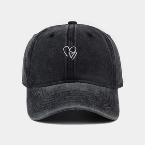 Gros plan d'une broderie de cœur blanc sur une casquette vintage noire délavée