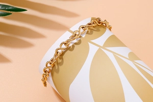 Close-up of gold infinity-link stainless steel bracelet on a decorative prop