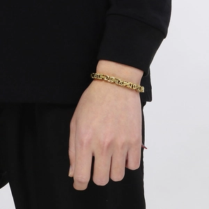 Detail of a gold stainless steel Byzantine chain bracelet worn on a model's wrist