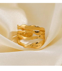 Détail d'une bague dorée multicouche ondulée avec texture martelée sur satin blanc