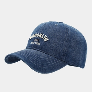 Détail macro de la broderie Brooklyn 3D blanche sur casquette en jean bleu foncé vintage
