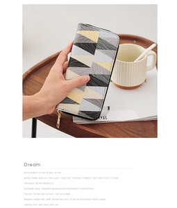 Detail showing hand holding a long zipper wallet with modern geometric triangle pattern