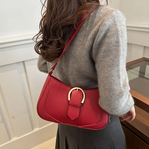 Close-up of red lychee pattern shoulder bag with golden D-ring hardware on a model