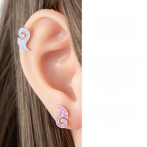 Macro shot of asymmetric crystal waves ear studs in blue and pink on model's ear