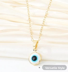 Detailed close-up of golden evil eye pendant with blue concentric circles on white silk