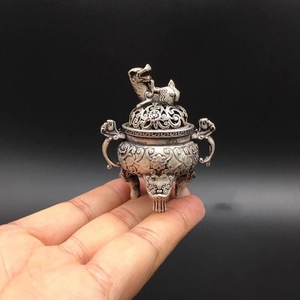 Close-up of a mini vintage silver censer with detailed floral relief and tripod legs