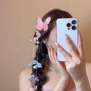 Detailed view of pink fabric butterfly hair clip with pearl tassels on braided hair