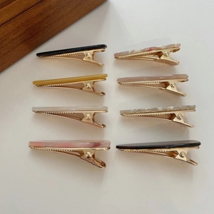 Detailed overhead view of assorted acetate hair clips with gold metal bases and patterns