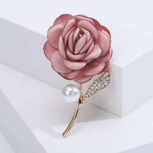 Macro shot of pink fabric rose brooch with gold leaves, rhinestones and a white pearl