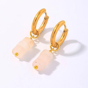 Vue détaillée de créoles dorées avec pendentifs cylindriques rose clair sur fond blanc