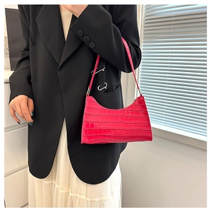Close-up of bright pink baguette bag with crocodile texture on black blazer