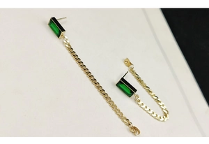 Detail of long gold titanium steel earrings with green rectangle stone and thin tassels