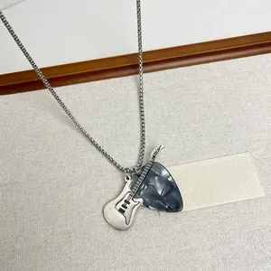 Detailed macro view of silver guitar and pick pendants on a pearl chain necklace