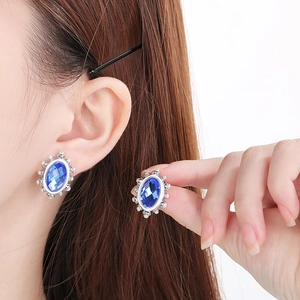 Macro detail of oval blue glass earring with shell bead border on a silver base