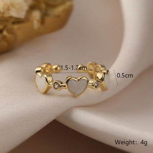 Detailed macro shot of gold-plated shell heart ring with cubic zirconia on silk background