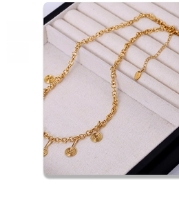 Close-up of gold chain necklace with spiral pendants and adjustable logo tag clasp