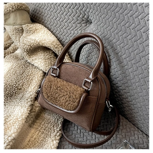 Detail of dark brown faux suede handbag featuring plush shearling flap and sturdy handles