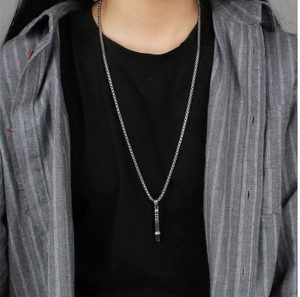 Silver whistle pendant necklace shown on a model with grey striped shirt and black top