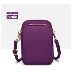 Detail of purple nylon crossbody bag featuring gold zippers and multi-layer pockets