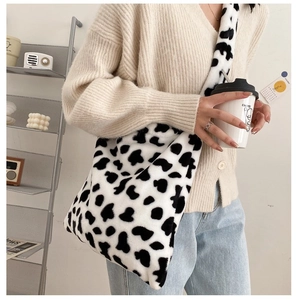 Cow pattern plush crossbody bag shown on a model in a stylish indoor home setting