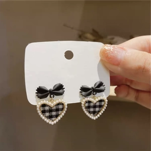Detail of s925 silver needle bow earrings with heart pearl and checkered pattern