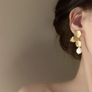 Elegant gold flower pearl earrings shown on a model with a sophisticated side profile