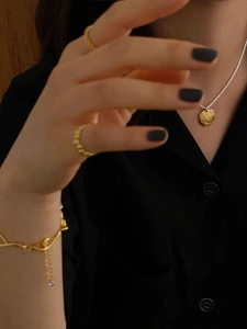 Artistic detail of a gold irregular textured pendant and rings on a model