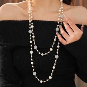 Close-up of double-layer vintage pearl necklace with tiger eye beads on black knitwear