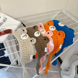 Detailed close-up of knitted bear hats in five colors with soft ear flaps and long ties