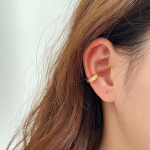 Close-up of golden textured ear cuff showing hammered irregular surface on a model's ear