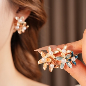 Macro detail of gold-plated flower earrings with colorful enamel petals and pearls
