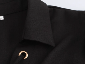 Detailed close-up of a black French pleated dress neckline with gold eyelet and S-size tag