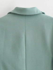 Detail view of smooth light green blazer fabric with clean stitching and back seam line