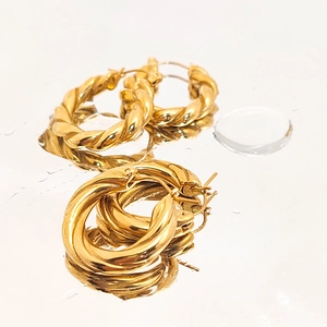 Detailed view of gold twisted hoop earrings with polished finish and mirror reflections