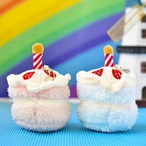 Macro view of pink and blue plush cake keychains with strawberry embroidery and candles