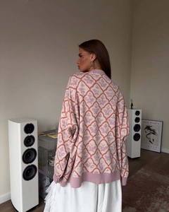 Back view of pink knit sweater with orange diamond patterns in modern interior