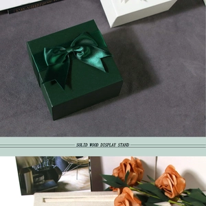 Close-up of a dark green gift box with a matching satin ribbon and bow detail