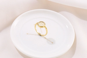 Detailed macro view of gold honeycomb zircon ring on white ceramic with S925 engraving